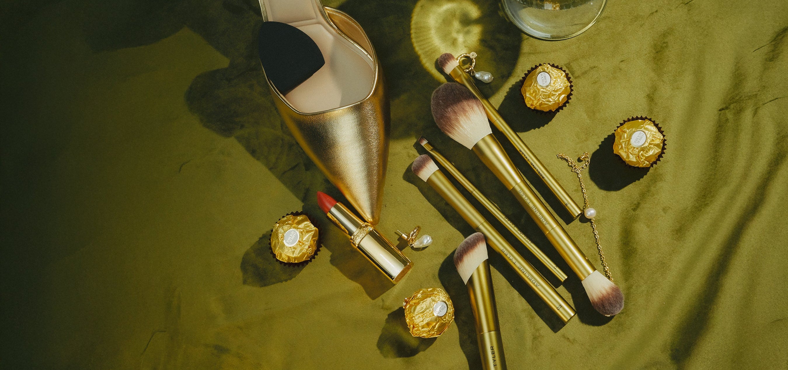 Makeup brushes and lip products on a green surface